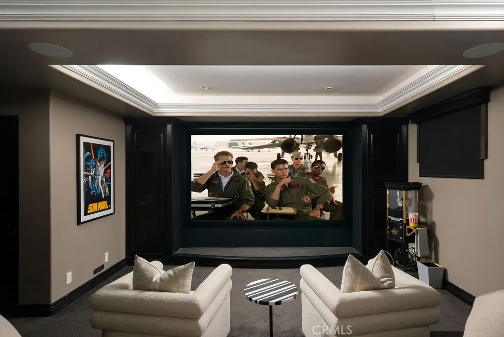 Private high end home theater featuring a large projection screen, tiered lounge seating, a built-in refreshment bar, and dramatic coffered ceilings—perfect for an immersive movie-night experience.