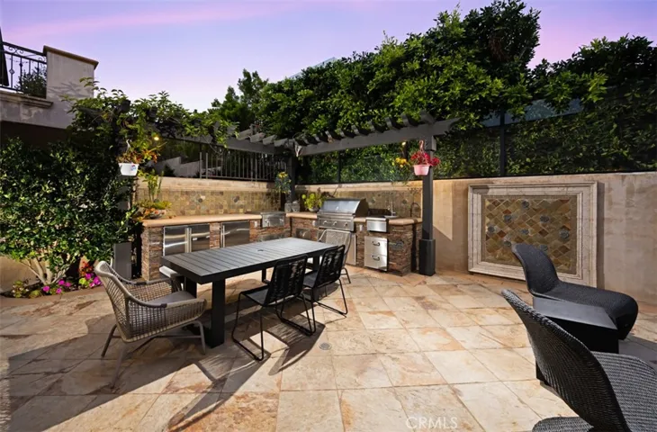 A private outdoor dining retreat flows seamlessly into multiple lounge areas and a fully equipped outdoor kitchen, creating an exceptional setting for alfresco entertaining surrounded by lush greenery.