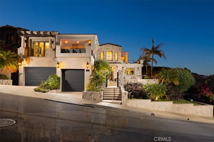 Striking Mediterranean-style architecture creates exceptional curb appeal, highlighted by lush landscaping, custom stonework, a rare double-height three-car garage with custom roll-up doors, and driveway parking for three additional vehicles.
