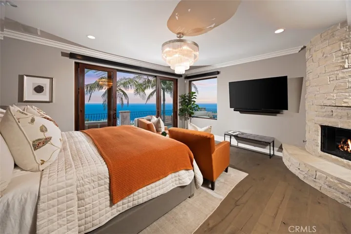 

Luxurious primary suite featuring automated roller shades, a romantic stone fireplace, and breathtaking ocean views enjoyed right from the comfort of bed.