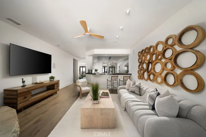 Spacious family room featuring wide-plank wood flooring, built-in media area, and adjacent bar seating—ideal for relaxed entertaining.