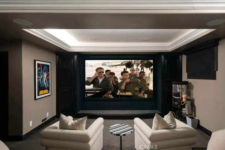 Private high end home theater featuring a large projection screen, tiered lounge seating, a built-in refreshment bar, and dramatic coffered ceilings—perfect for an immersive movie-night experience.