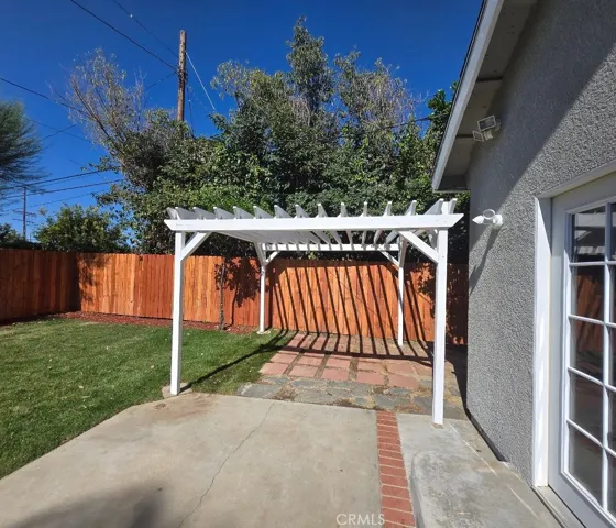 The charming pergola overlooks a spacious backyard designed for outdoor living and entertaining