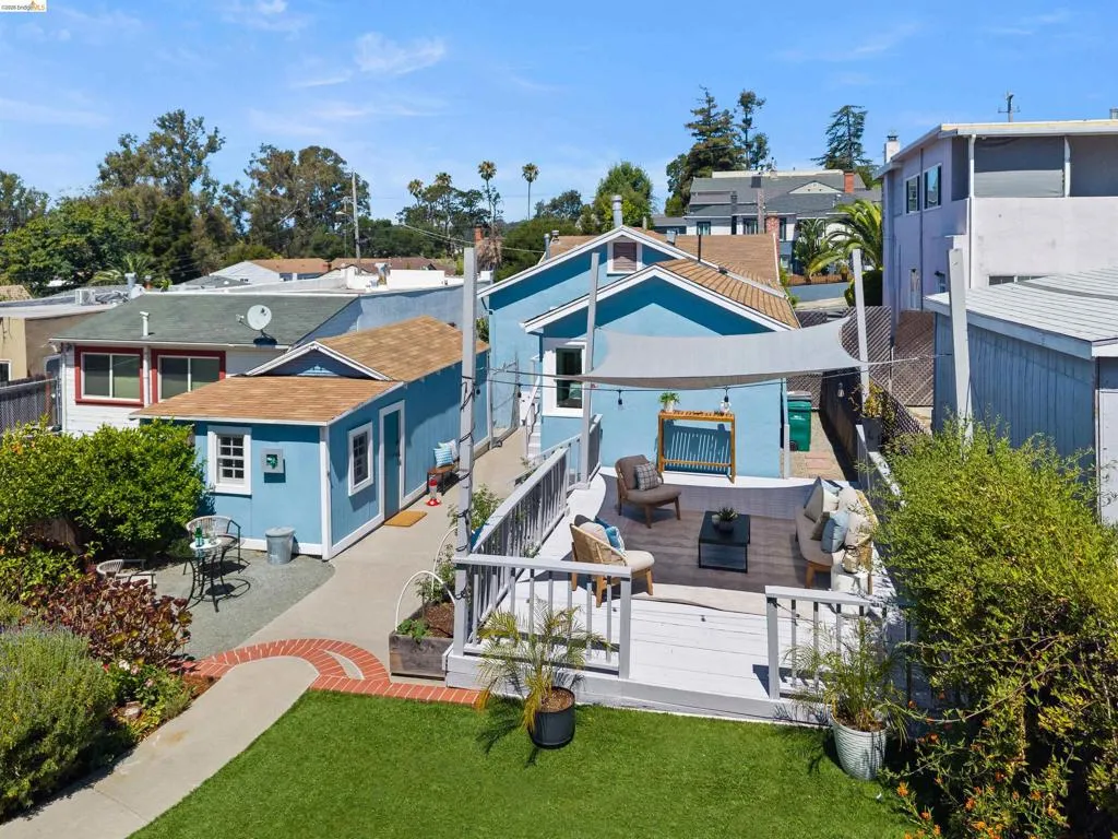 Multi-level property featuring a main structure, detached outbuilding, and an expansive back yard including a turf lawn and large wood deck