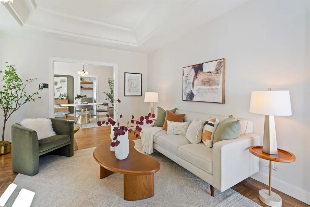 Living area featuring wood-finish flooring, a tray ceiling, and a broad archway