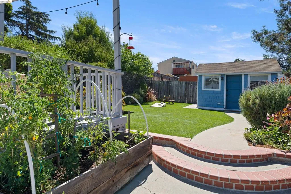Expansive backyard featuring a turf lawn, concrete pathway, and mature landscaping