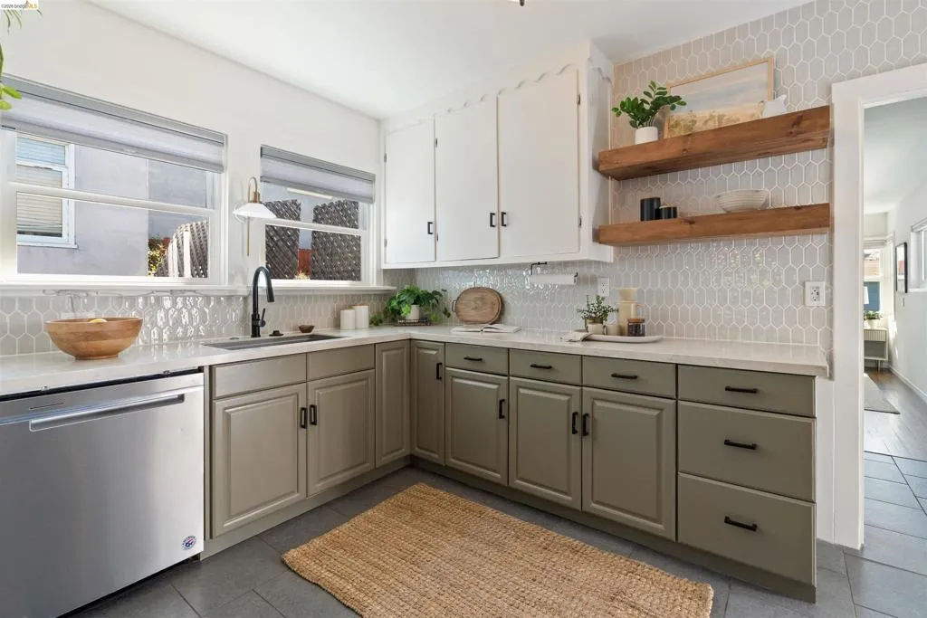 Kitchen featuring light gray picket tile backsplash, white upper cabinetry, and contrasting green lower cabinetry with black hardware