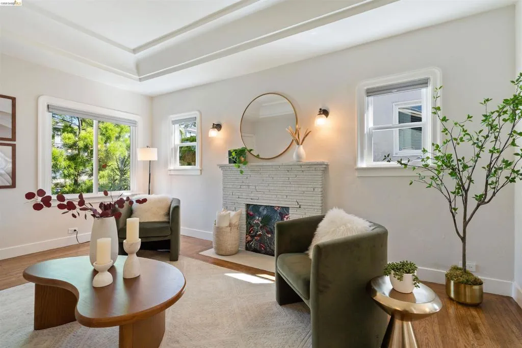 Living area featuring a tray ceiling, recessed fireplace with stacked stone surround, wood-finish flooring, white baseboards, and multiple​​‌​​​​‌​​‌‌​​‌​​​‌‌​​​‌​​‌‌​​‌‌​​‌‌​​​​ windows