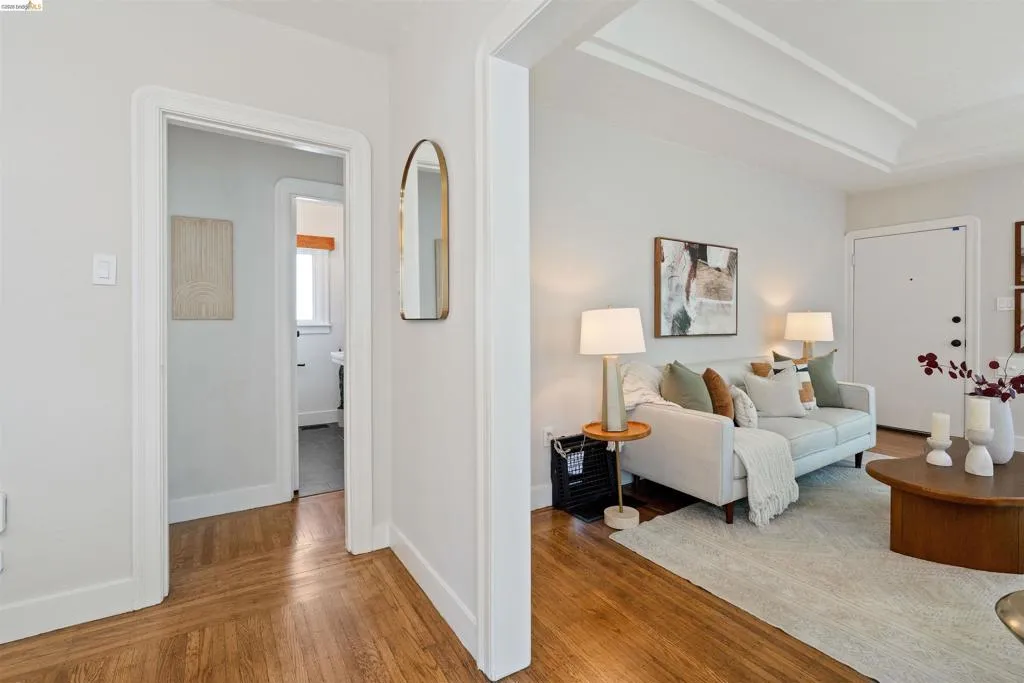 Hardwood flooring featuring a herringbone pattern, white baseboards, and a coffered ceiling in the living area