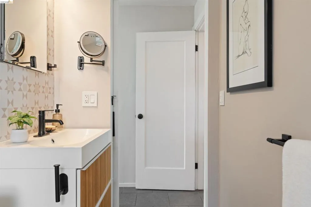 ensuite Bathroom vanity with integrated sink, matte black faucet, and patterned backsplash