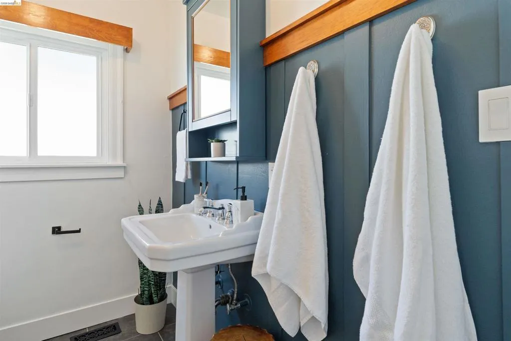 Hall bath contains Pedestal sink with chrome fixtures, board and batten wall detailing, built-in medicine cabinet
