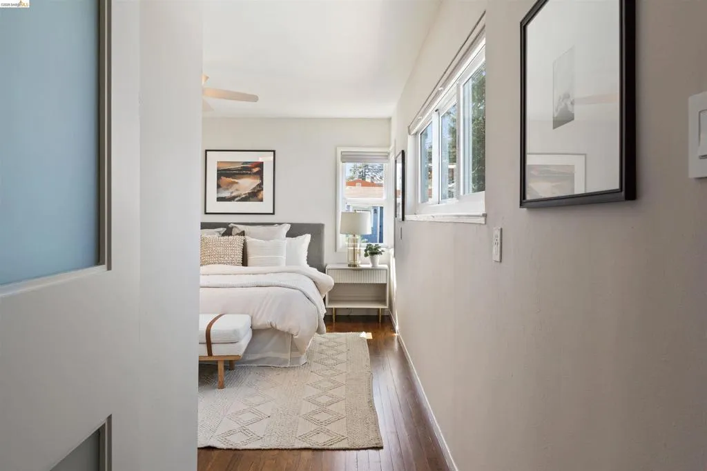 Primary bedroom has hardwood floor, a ceiling fan, multiple windows, two closets, and an ensuite bathroom.