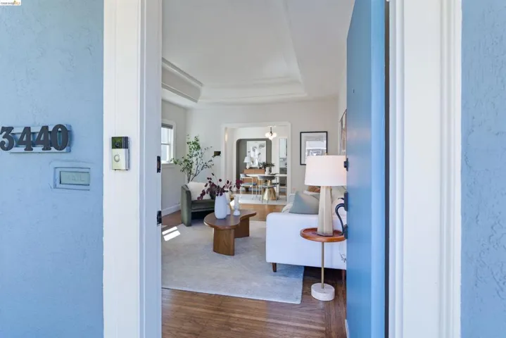 Bright interior featuring wood-finish flooring, a tray ceiling, and an arched doorway