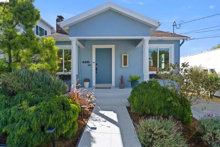Light blue exterior with white trim and a covered entry, featuring a substantial front yard with mature landscaping