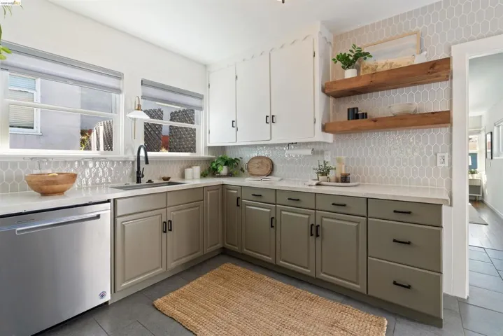 Kitchen featuring light gray picket tile backsplash, white upper cabinetry, and contrasting green lower cabinetry with black hardware