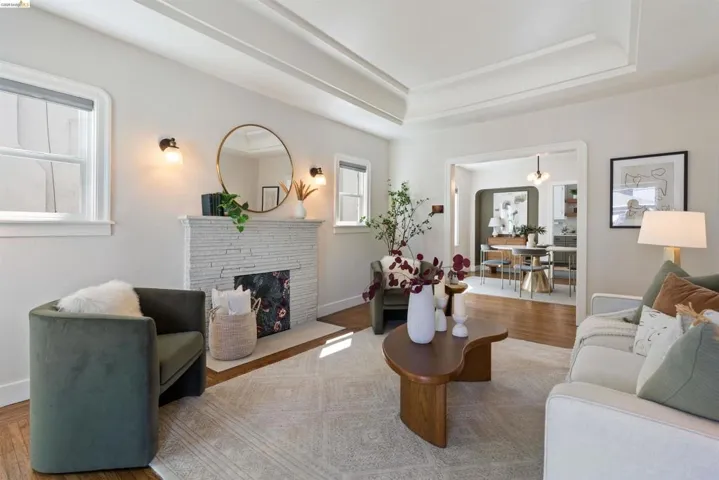Living area featuring a textured fireplace surround with sconce lighting, wood-finish flooring, a coffered ceiling, and a broad entry to a dining space