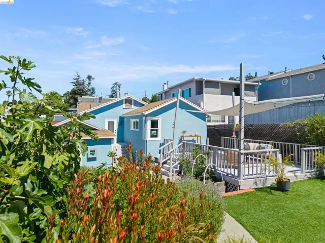 Expansive outdoor decking featuring a sun shade, artificial turf lawn, and established perimeter landscaping
