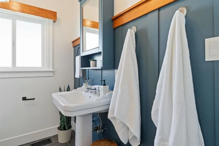 Hall bath contains Pedestal sink with chrome fixtures, board and batten wall detailing, built-in medicine cabinet