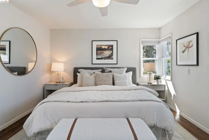 Primary bedroom has hardwood floor, a ceiling fan, multiple windows, two closets, and an ensuite bathroom.