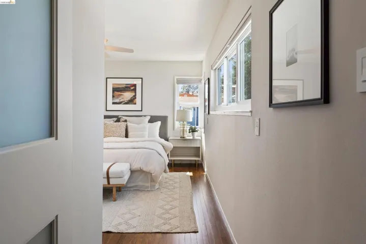 Primary bedroom has hardwood floor, a ceiling fan, multiple windows, two closets, and an ensuite bathroom.