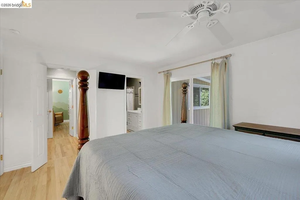 Spacious room featuring wood-finish flooring, a ceiling fan, and white walls