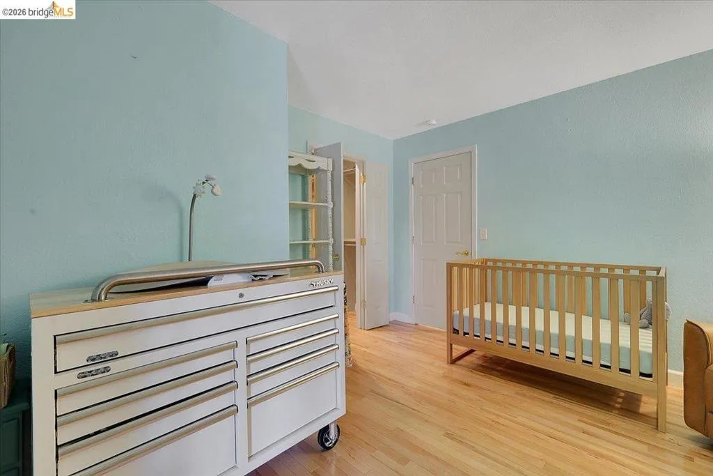 Light-filled room featuring wood-finish flooring, two panel doors, and a closet with built-in shelving