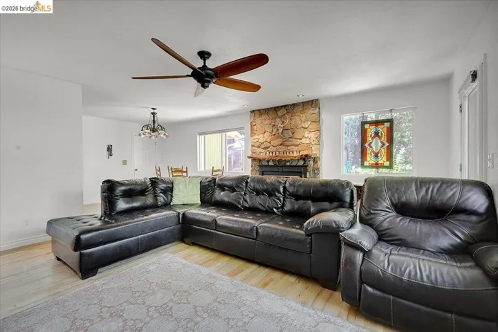 Living area featuring light wood-finish flooring, a stone fireplace with a dark mantel, and recessed lighting