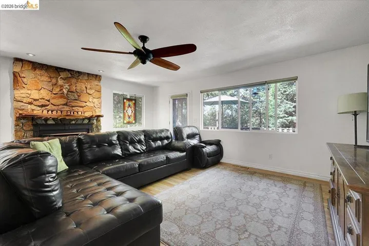 Living area featuring a stone accent wall with a fireplace, recessed lighting, and a multi-blade ceiling fan