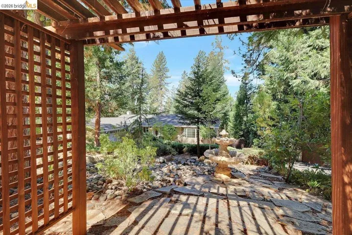 Wood pergola structure with lattice detailing framing a stone patio
