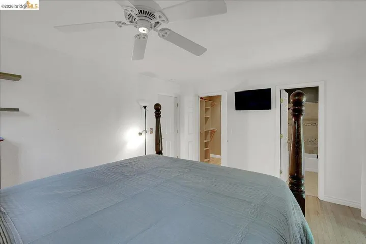Bedroom featuring a ceiling fan with integrated lighting, wood-finish flooring, and light-colored wall paint