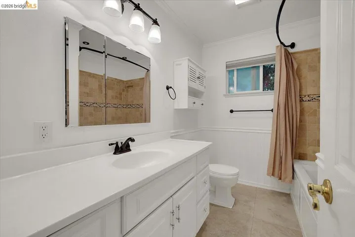 Bathroom featuring a white vanity with integrated sink, bronze-finish faucet, and a large wall-mounted mirror