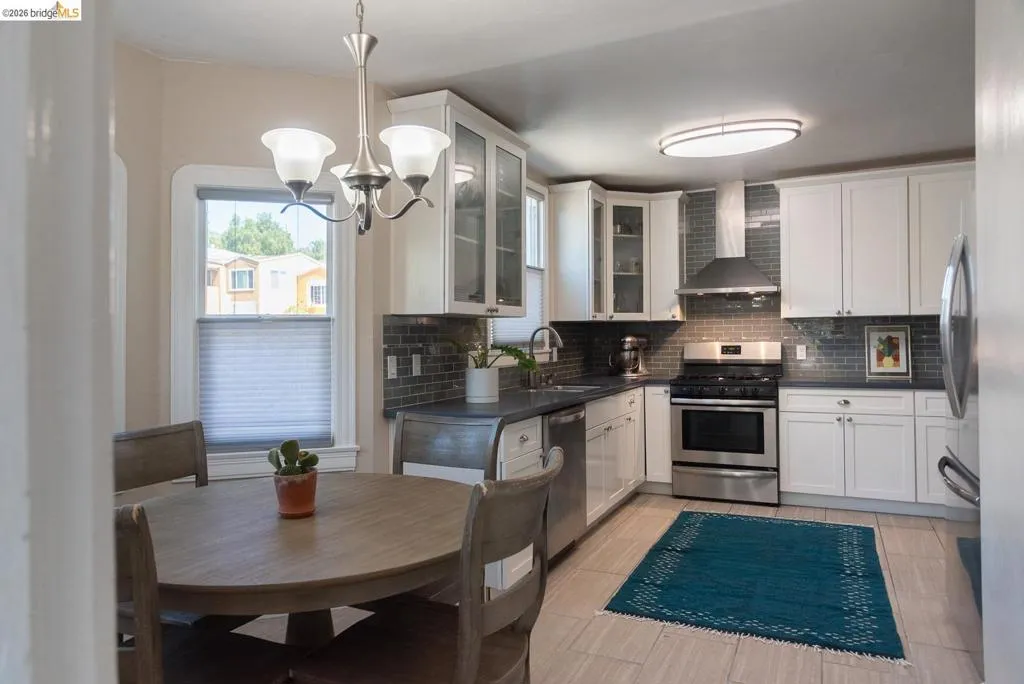 Kitchen featuring white cabinetry, stainless steel appliances, dark countertops, and a subway tile backsplash
