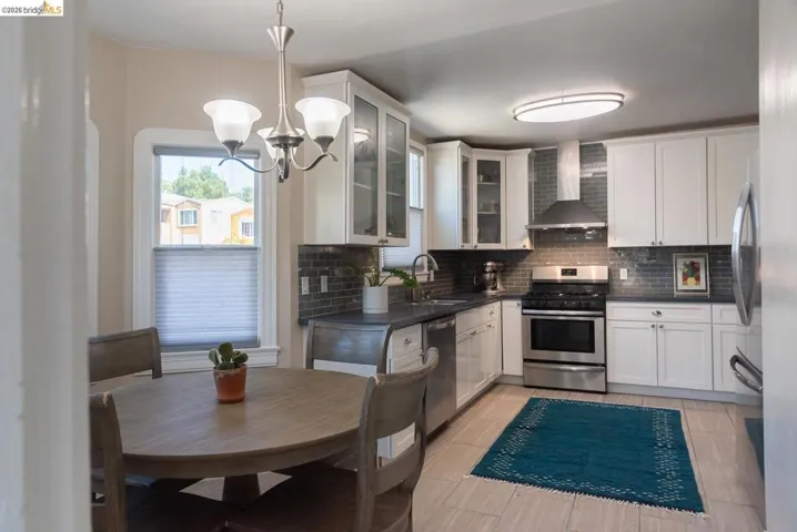 Kitchen featuring white cabinetry, stainless steel appliances, dark countertops, and a subway tile backsplash