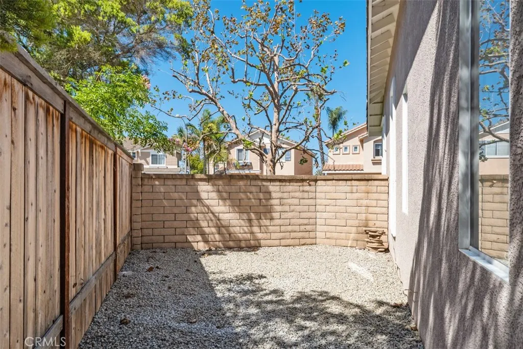 Side Yard: Gravel-finished side yard with wood fencing and a block wall provides a low-maintenance utility or storage area.