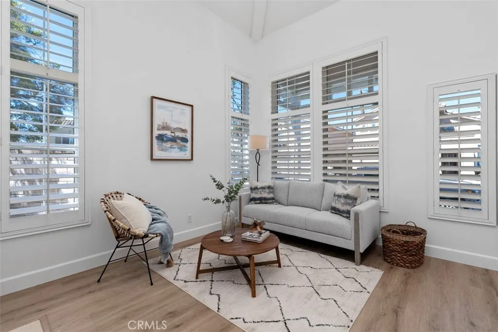 Living Room: Multiple tall windows with plantation shutters bring in abundant natural light, while the vaulted ceiling enhances the open feel of the room.