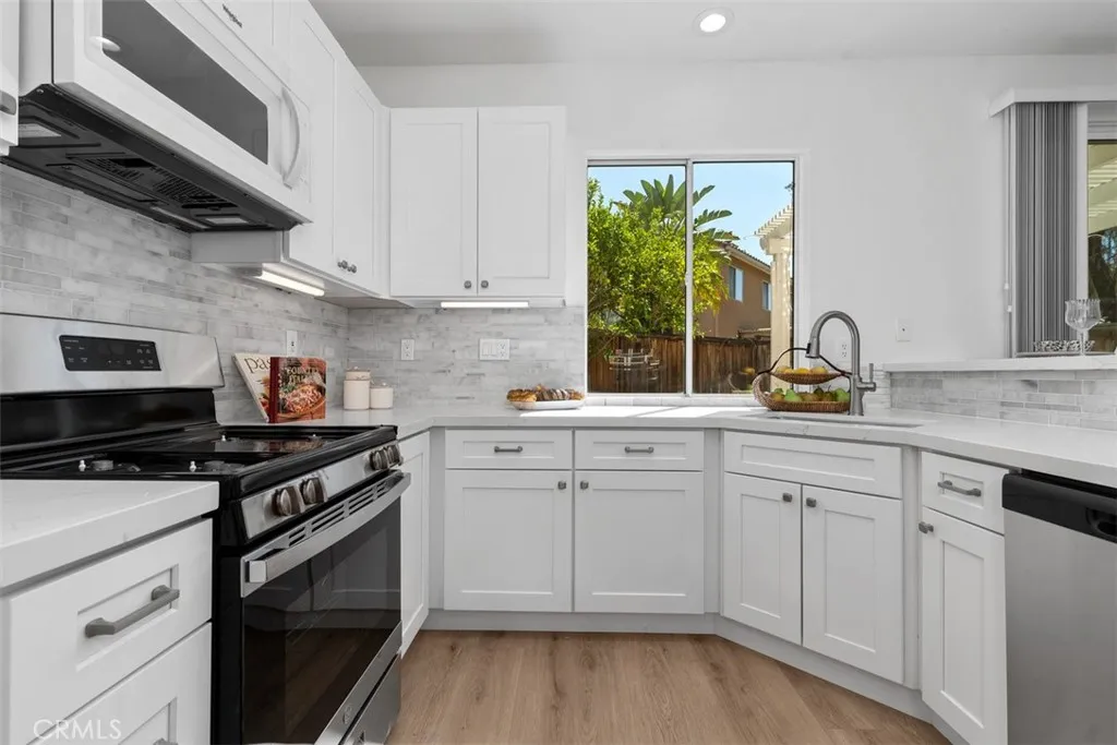 Kitchen: Another angle highlights the generous counter space, stainless-steel appliances, under-cabinet lighting, and bright backyard-facing window.