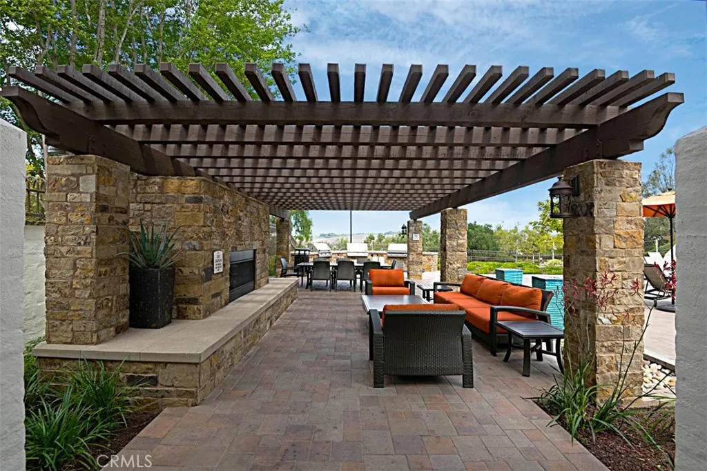 Community Lounge / Barbecue Area: Open-air gathering space combines shaded seating, stone fireplace features, and convenient access to the barbecue area.