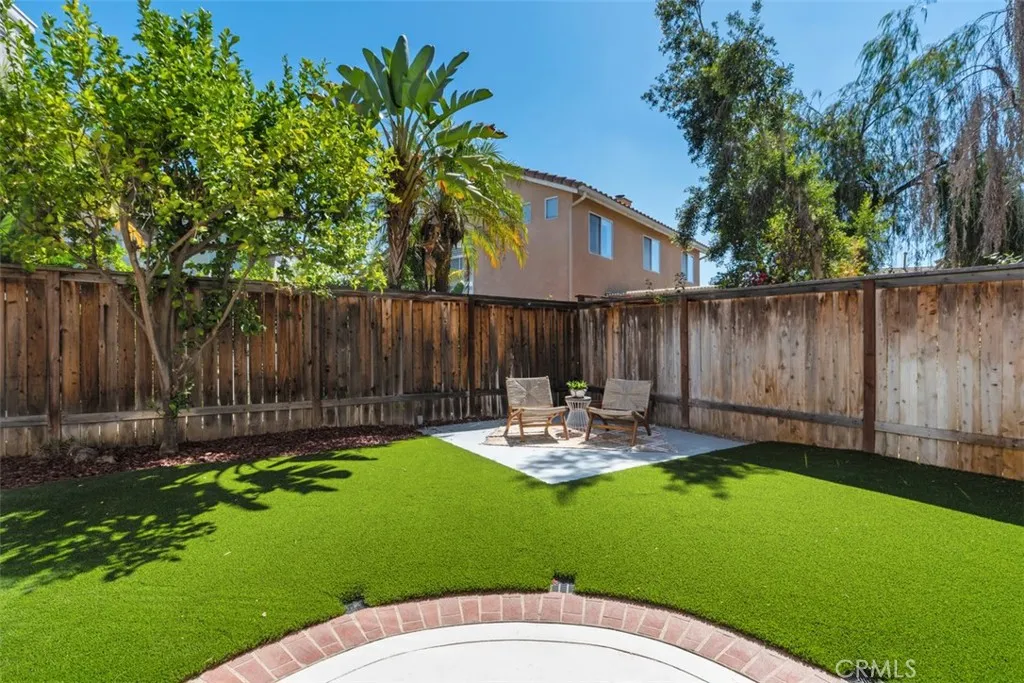 Backyard: Enclosed yard with low-maintenance turf, mature landscaping, and a dedicated seating area for outdoor relaxation.