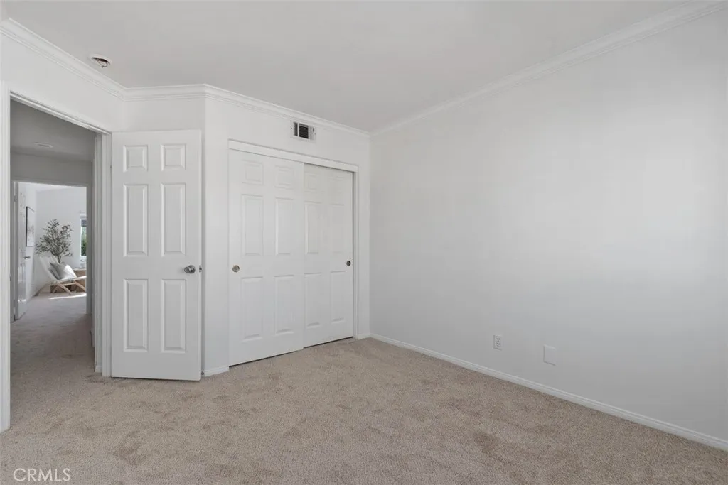 Secondary Bedroom: Alternate view highlights the room’s closet storage, crown molding, neutral finishes, and flexible floor space.