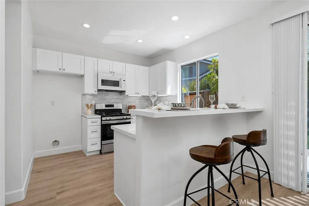 Kitchen / Breakfast Bar: A raised breakfast bar adds casual seating, while white cabinetry, stainless-steel appliances, and an open layout connect the kitchen to the dining area.