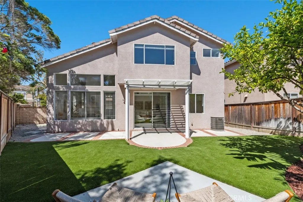 Backyard: Rear exterior view showcases the two-story home, expansive windows, pergola-covered patio, and low-maintenance turf yard.