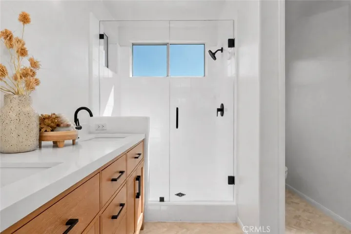 Virtually Enhanced - Primary Bathroom: The walk-in shower features clean white tile, black fixtures, and an upper window that brings daylight into the space.