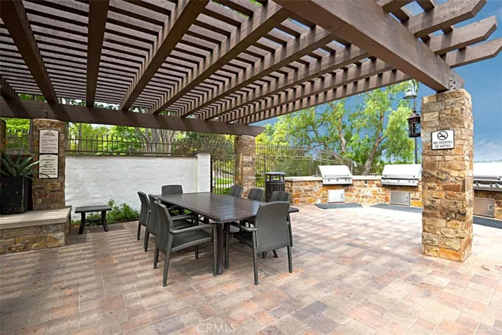 Community Dining / Barbecue Area: Shaded dining area with tables, stone columns, and nearby built-in grills supports outdoor meals and entertaining.