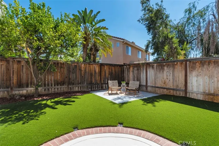 Backyard: Enclosed yard with low-maintenance turf, mature landscaping, and a dedicated seating area for outdoor relaxation.