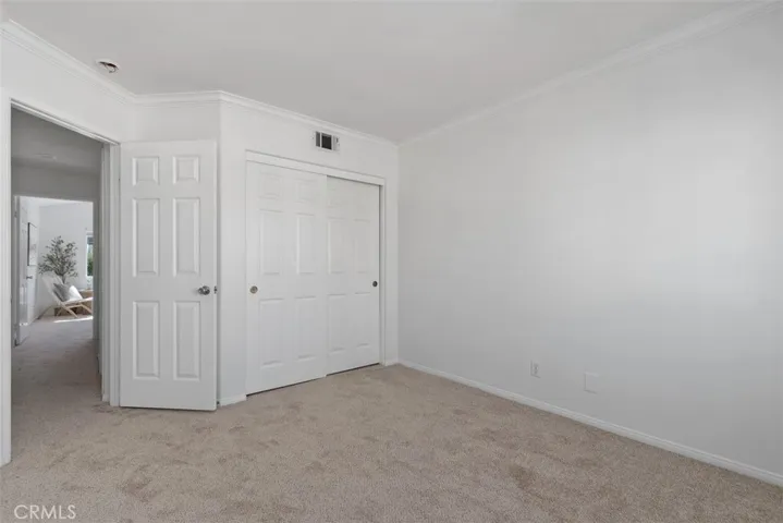 Secondary Bedroom: Alternate view highlights the room’s closet storage, crown molding, neutral finishes, and flexible floor space.
