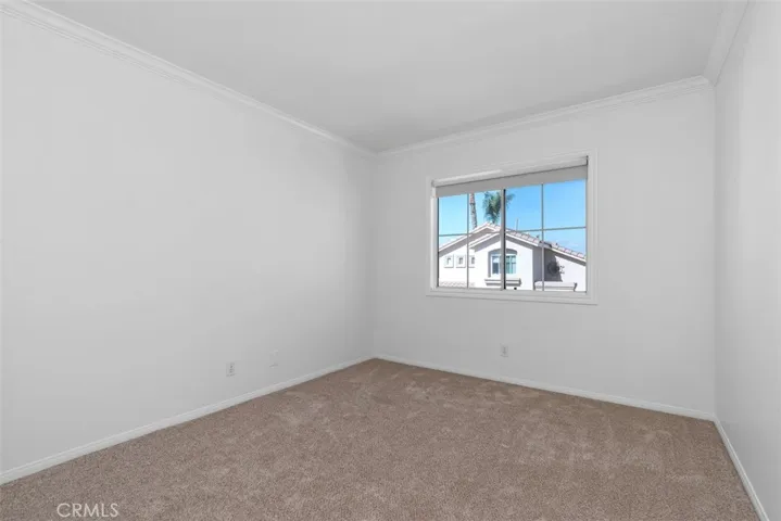 Secondary Bedroom: Bright bedroom with soft carpeting, crown molding, and a window that provides natural light.