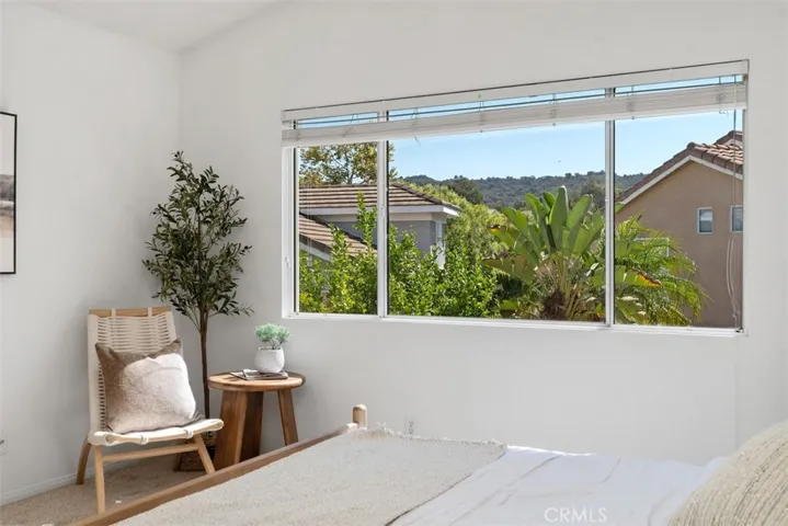 Primary Bedroom: The oversized window frames leafy neighborhood and hillside views while brightening the room with natural light.