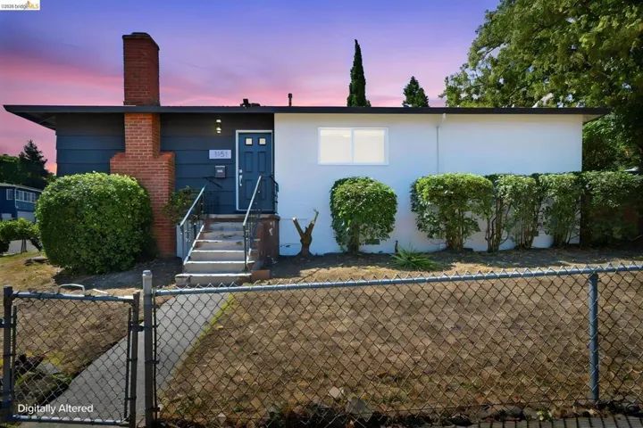 Single-story residence featuring a brick chimney, a dark blue paneled front door, and a concrete stairway with metal railings