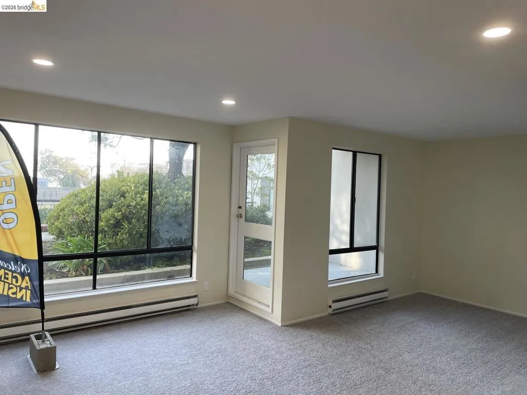 Bright interior space featuring light-colored walls and grey carpeting