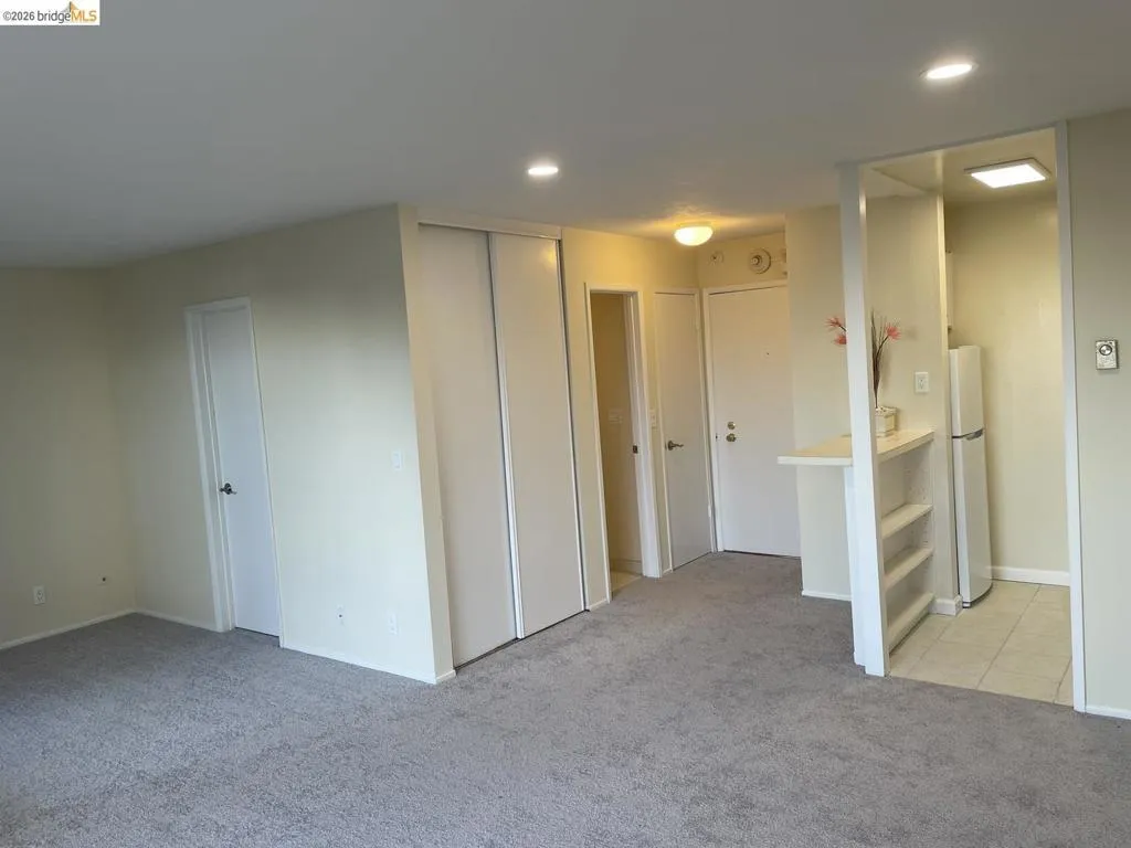 Carpeted living area featuring recessed lighting, a built-in closet with sliding doors, and a breakfast bar with shelving